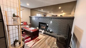 A modern living room with a fireplace, a dining table, and a red and white rug. - Private Bachelor Unit close to St. Clair College walking distance  (Windsor)