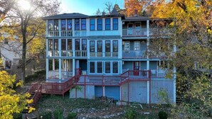 A multi-story building with a balcony on the second floor, a stone wall in front, and a sign indicating private parking. - Downtown Primrose Piedmont House (Eureka Springs)