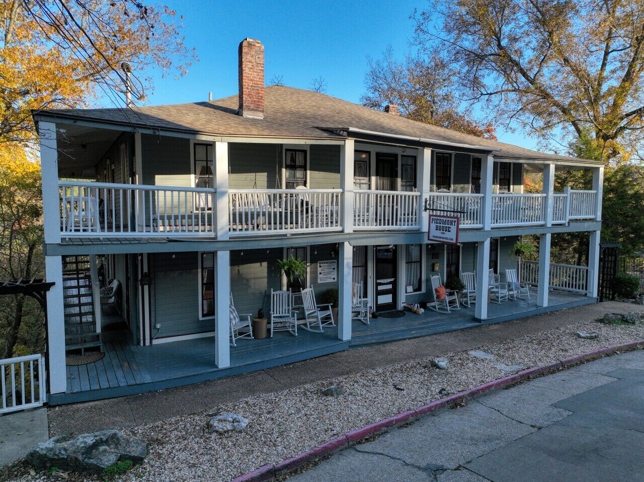 A two-story building with a porch, outdoor seating, and a chimney.