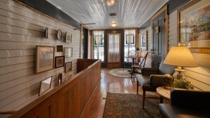A wooden interior with a bench, framed pictures, and a lamp. - Downtown Victorian St Piedmont (Eureka Springs)