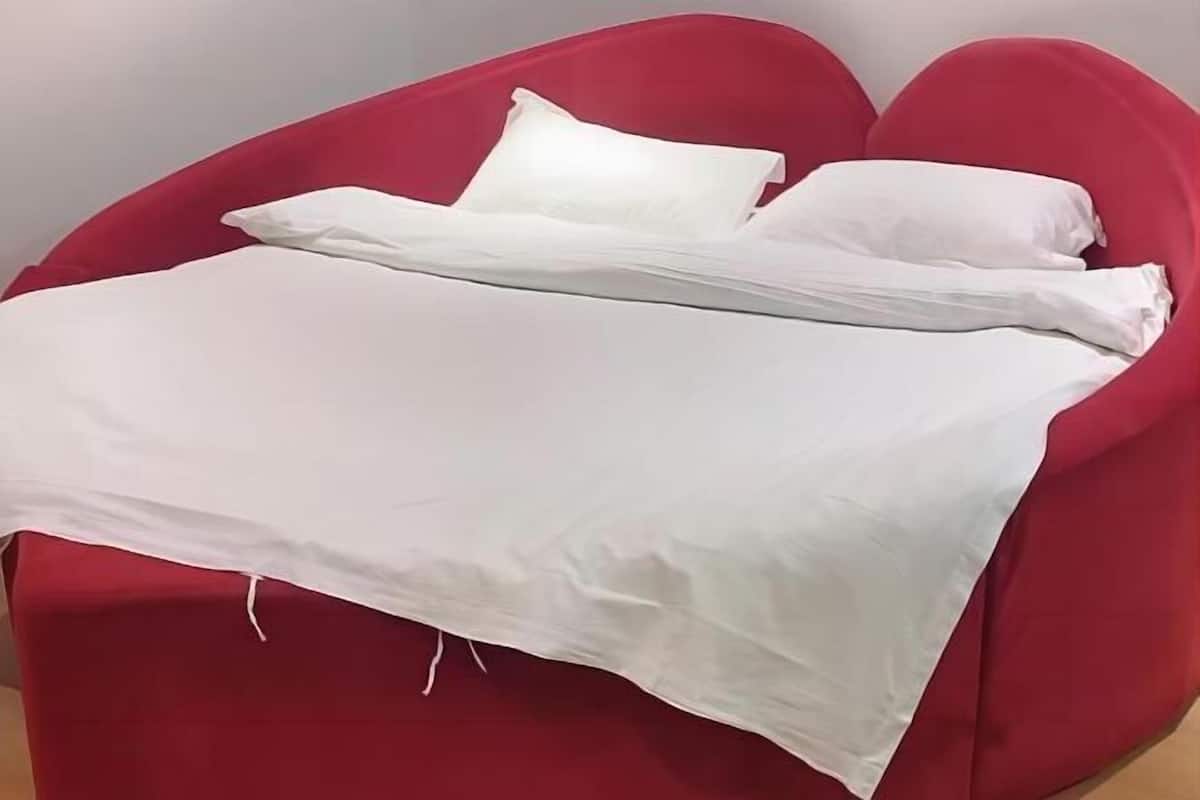 Una silla roja con un colchón y almohadas blancos.