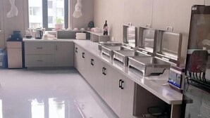 A modern kitchen with stainless steel appliances, a countertop with a coffee maker, and a fish tank. - Pandora Fashion Hotel (Yanji Yanbian University West Market Branch) (Yanji)
