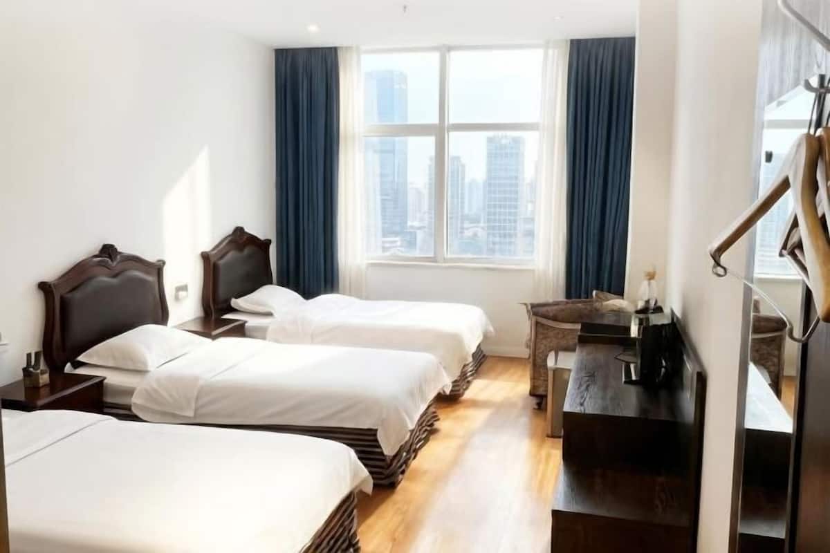 Habitación de hotel con dos camas, un escritorio, una silla y vistas a la ciudad por la ventana.