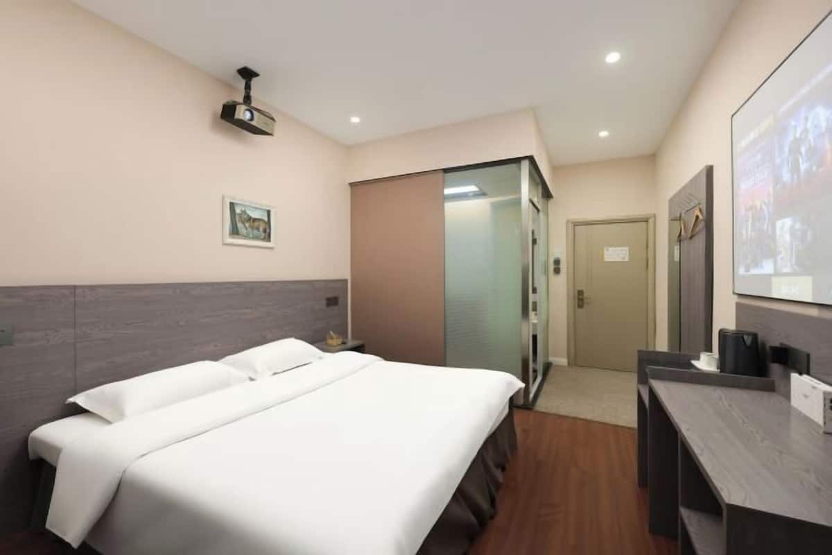 Una habitación de hotel con cama, escritorio, televisor y puerta.