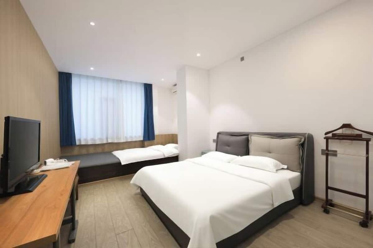 Una habitación de hotel con una cama, un escritorio, un televisor y una ventana con cortinas.