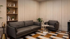 A modern living room with a sofa, a smaller armchair, a coffee table, and a bookshelf with decorative items. - Pandora Fashion Hotel (Yanji Yanbian University West Market Branch) (Yanji)