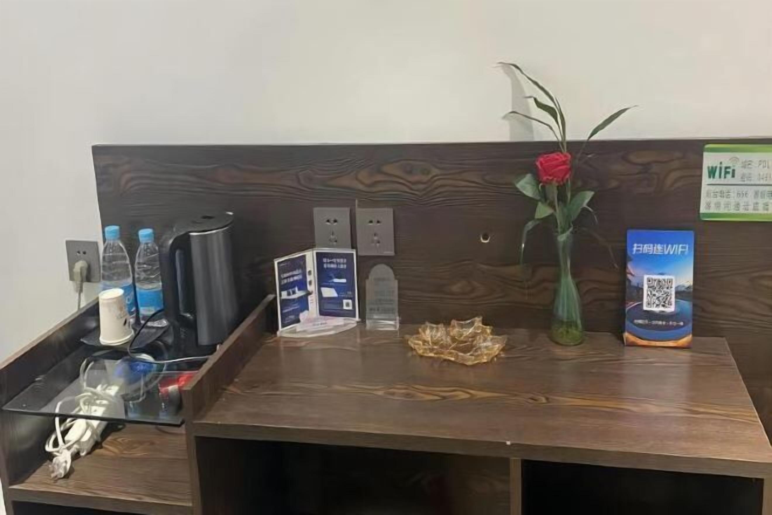 A reception desk with a wooden finish, a vase with a red rose, a QR code for WiFi, and a sign indicating WiFi availability.