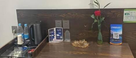 A reception desk with a wooden finish, a vase with a red rose, a QR code for WiFi, and a sign indicating WiFi availability.