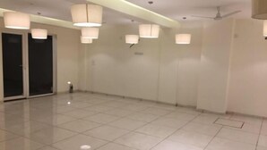 Una habitación amplia y bien iluminada, con suelo de baldosas, ventiladores de techo y lámparas colgantes.