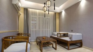 A modern living room with a sofa, wooden chairs, a coffee table, and a ceiling light fixture. - Taihe Kaida Business Hotel (Taihe People's Hospital) (Taihe)