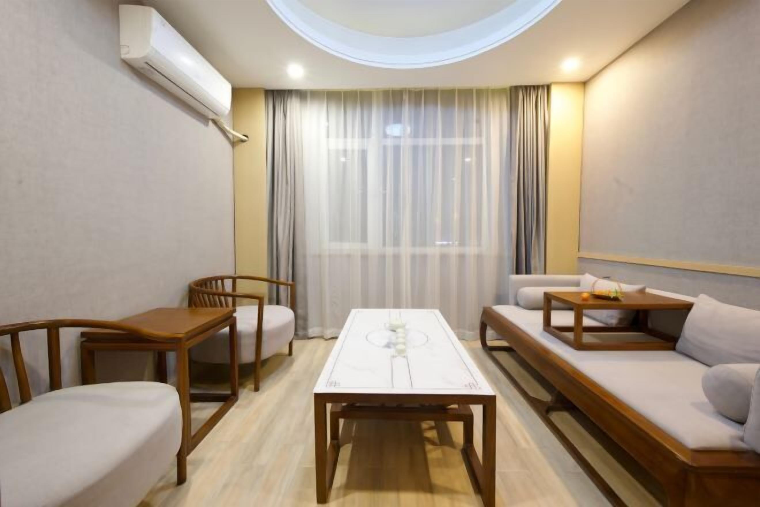 Une chambre d’hôtel moderne avec une lucarne ronde, une table centrale, un canapé et un fauteuil.