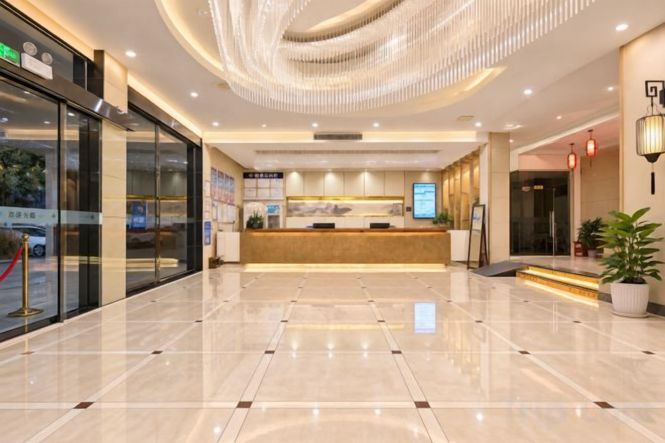 A hotel lobby with a reception desk, a glass storefront, and a polished floor.