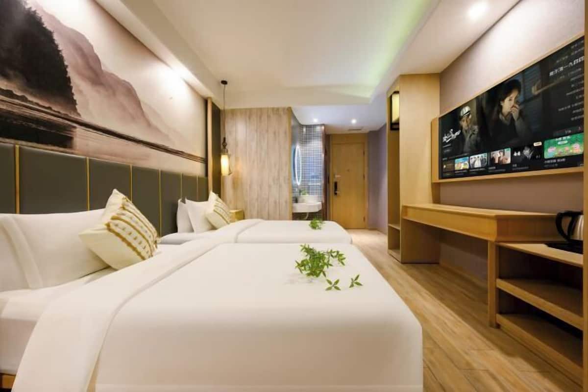 Une chambre d’hôtel moderne avec un grand lit, un écran de télévision et une œuvre d’art accrochée au mur.