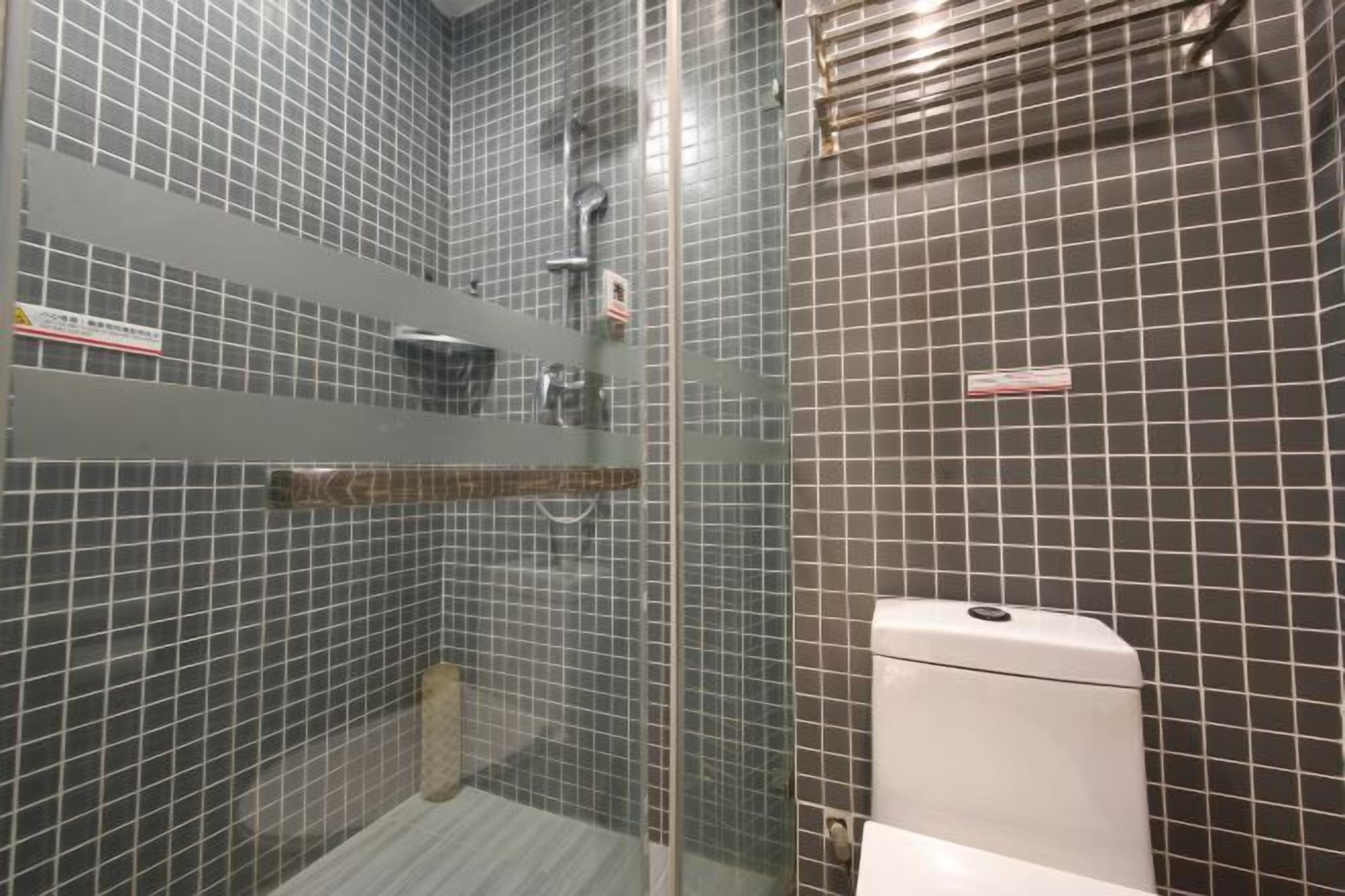 A bathroom with a glass shower enclosure, tiled walls, and a white toilet.