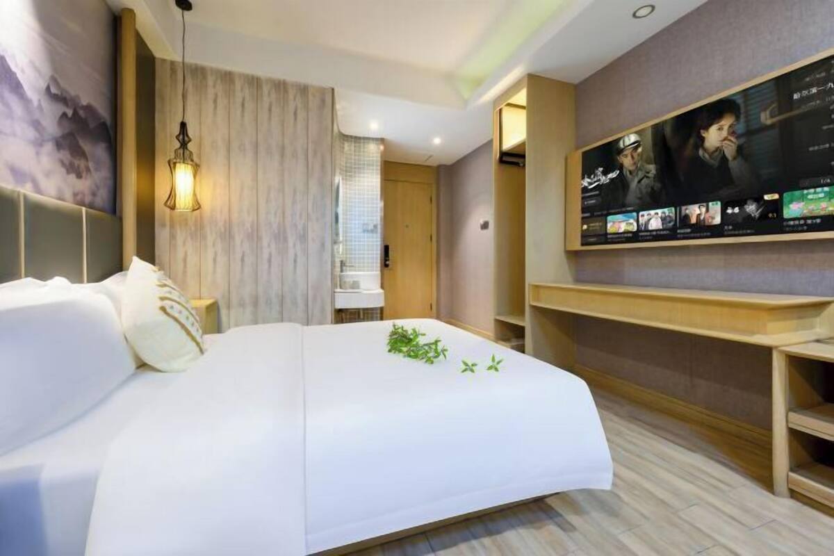Une chambre d’hôtel avec un lit, un téléviseur fixé au mur et un plancher en bois.