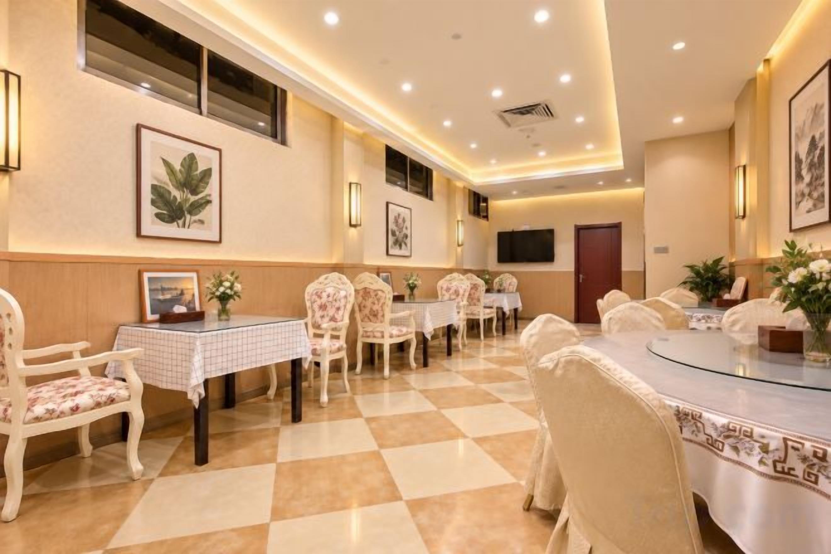 A hotel dining area with round tables, chairs, and a checkered floor.