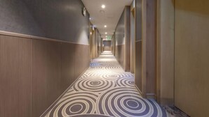 A hotel corridor with a patterned carpet, wooden paneling on the walls, and a series of doors leading to rooms. - Taihe Kaida Business Hotel (Taihe People's Hospital) (Taihe)