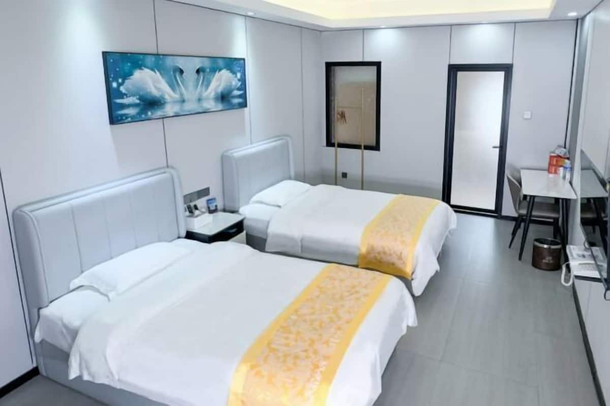 Une chambre d’hôtel avec deux lits, un bureau, une chaise, un tableau et une porte.
