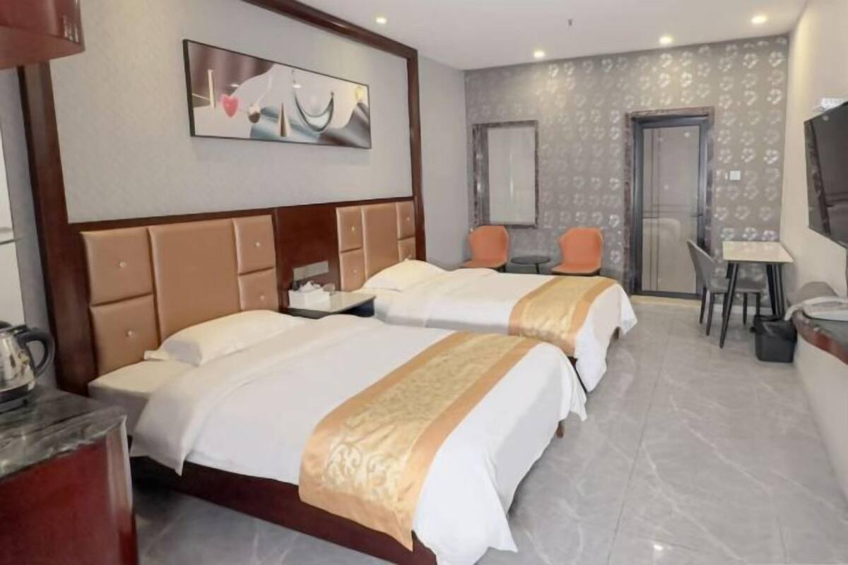 Une chambre d’hôtel avec deux lits, un bureau, des chaises et un téléviseur.