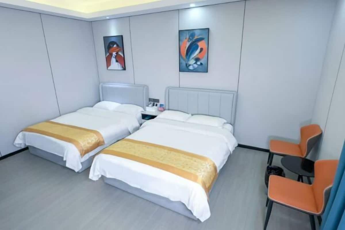 Une chambre d’hôtel avec deux lits, une petite table, deux chaises et des œuvres d’art accrochées aux murs.