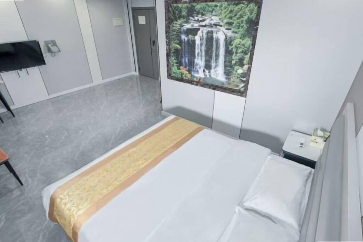 Une chambre d’hôtel avec un lit, une table de chevet, un téléviseur et un tableau représentant une cascade accroché au mur.