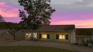 A two-story house with a front porch, a garage, and a small shed. - Lakefront Retreat •  King Suite • Covered Deck • Firepits • Sleeps 8 (Falls of Rough)