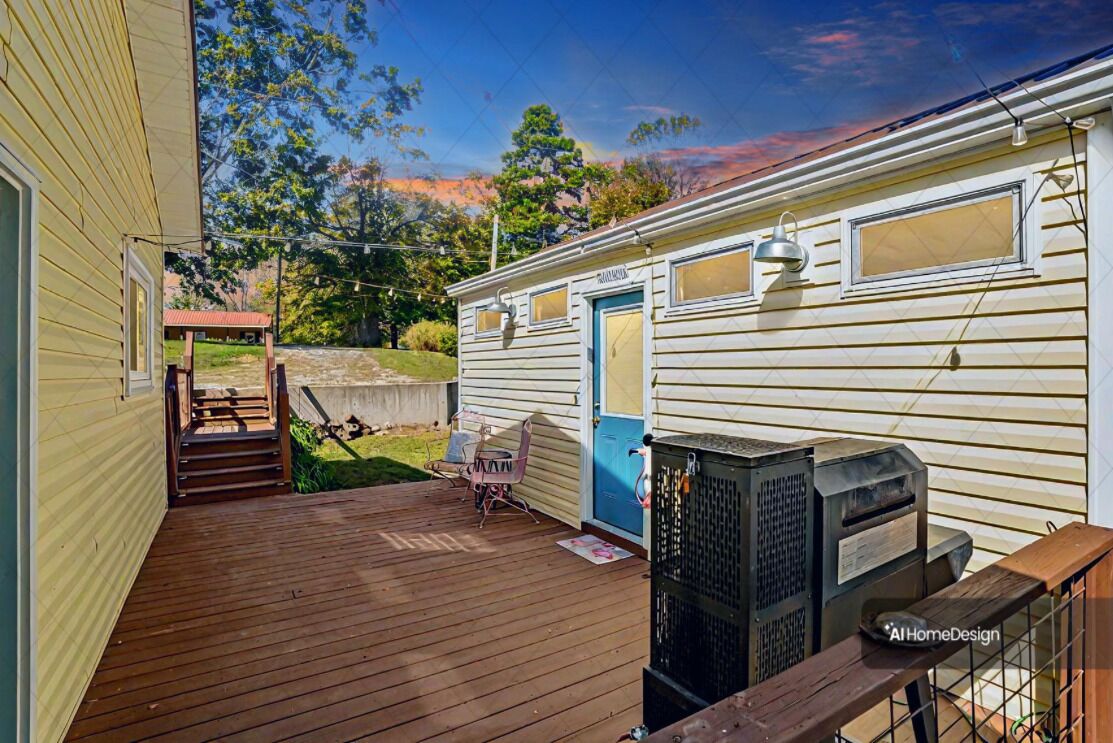 Uma casa móvel com deck de madeira, porta azul e um pequeno alpendre com cadeira e mesa.
