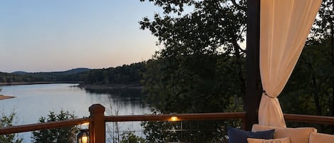 A deck with a fire pit, seating area, and a view of a lake.
