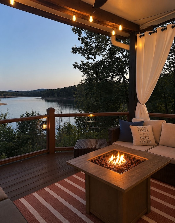 Une terrasse dotée d’un foyer extérieur, d’un espace salon et offrant une vue sur un lac.