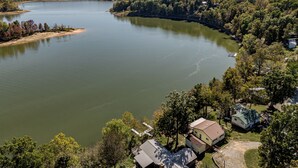 A lakeside property with a dock, a small house, and a larger building with a sloped roof. - Lakefront Retreat •  King Suite • Covered Deck • Firepits • Sleeps 8 (Falls of Rough)