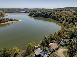 A lakeside property with a dock, a small house, and a larger building with a sloped roof.