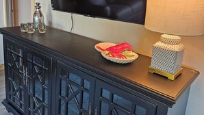 Un salon moderne avec un meuble de rangement en bois foncé pour l’équipement audiovisuel, un téléviseur à écran plat fixé au mur et une lampe décorative.