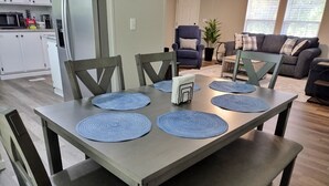 Un coin repas avec une table rectangulaire, quatre sets de table bleus et des chaises assorties.
