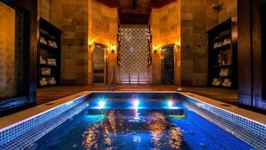 A swimming pool with blue lighting, surrounded by stone walls and wooden beams. - 2BR Grand Luxxe Residence loft RM (Playa del Carmen)