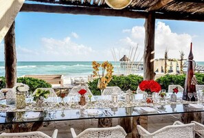 Un espace extérieur aménagé pour les repas, avec une table en verre pouvant accueillir six personnes, offrant une vue sur l’océan.
