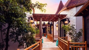 A wooden deck with a pergola, stone walls, and hanging lanterns. - 2BR Grand Luxxe Residence loft RM (Playa del Carmen)