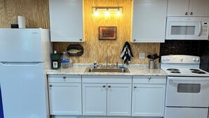 A kitchen with white cabinets, a built-in microwave, a stove, and a refrigerator. - Bass Lodge - Lakefront - New (Commerce)
