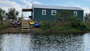 A green house by a lake with a dock and kayaks. - Bass Lodge - Lakefront - New (Commerce)