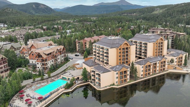 Un complexe hôtelier comprenant plusieurs bâtiments, une piscine centrale et un lac.