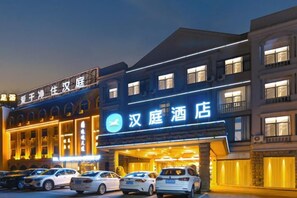 A hotel with a prominent sign, multiple floors, and a parking lot with several cars. - HanTing Hotel (Cixi Longshan) (Cixi)