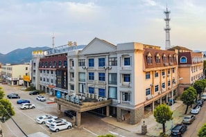 A multi-story hotel with a central courtyard, a parking lot, and a view of the surrounding urban area. - HanTing Hotel (Cixi Longshan) (Cixi)
