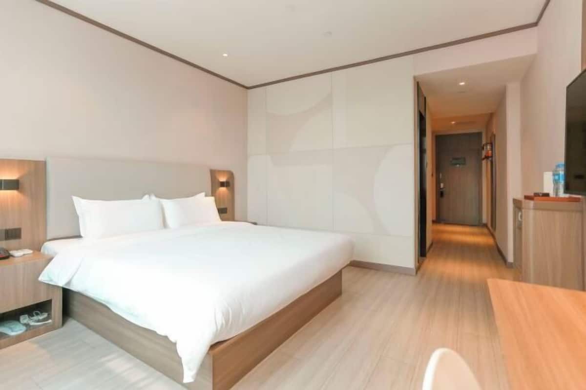 Una habitación de hotel moderna con una cama grande, mesitas de noche y un escritorio de madera.