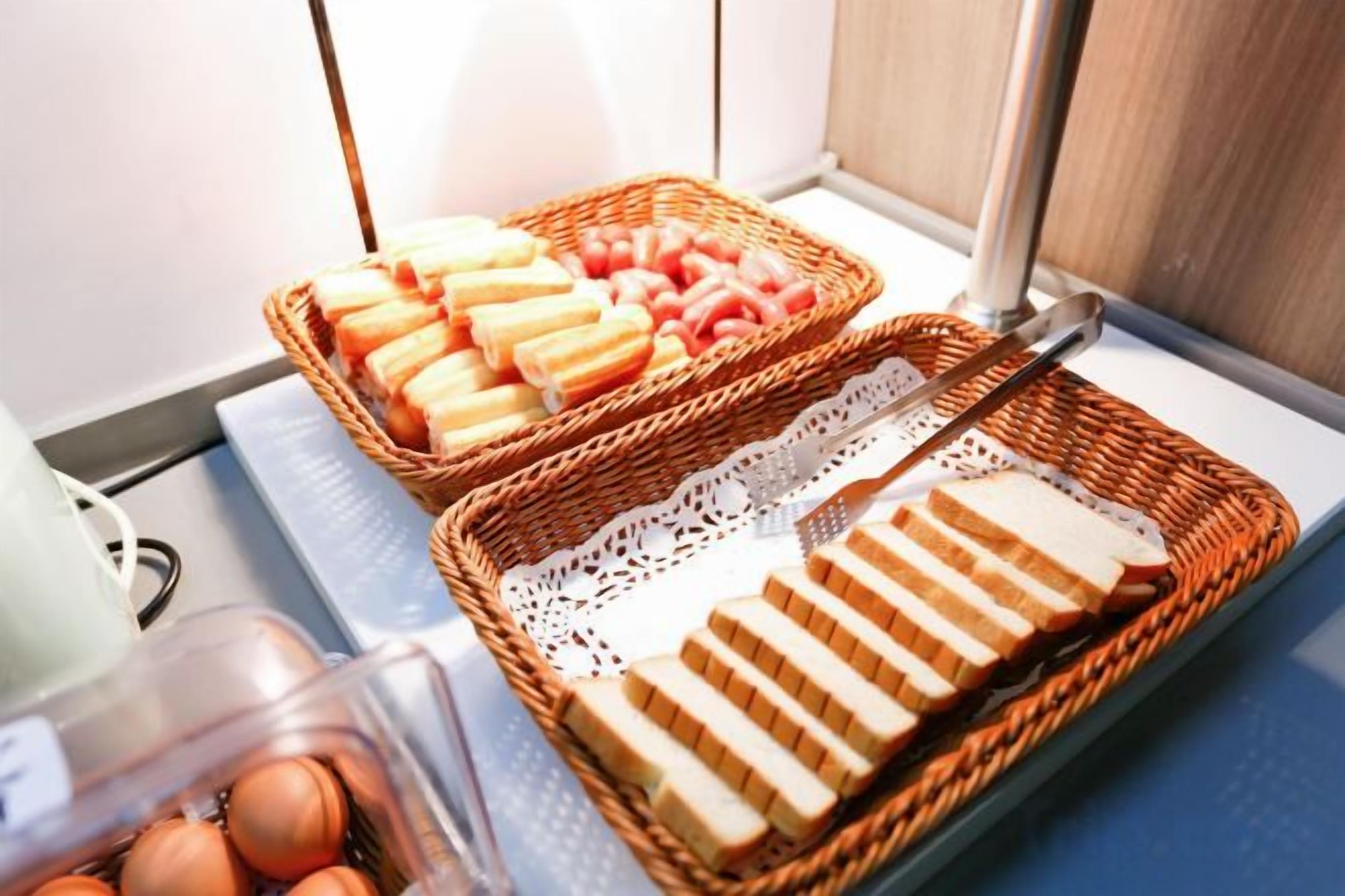 Dos cestos de mimbre con pan rebanado y un recipiente de plástico con huevos sobre una encimera.