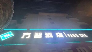 Un letrero de hotel con texto iluminado, un logotipo y una tira de luz de neón.