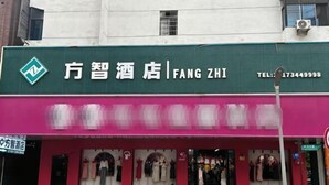 Fachada de hotel con un cartel verde que muestra el nombre '方智酒店' y un número de contacto.