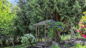 A gazebo in a garden with surrounding trees and flowering plants. - Tranquil 2-bed SeaTac Hideaway! (SeaTac)