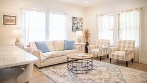 A living room with a sofa, armchairs, a coffee table, and a dining table. - Perfect location in Ocean Springs! Walk to downtown & beach! Mother's Place (Ocean Springs)