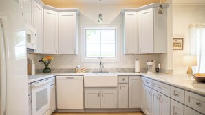 A modern kitchen with white cabinets, a built-in microwave, and a window above the sink. - Perfect location in Ocean Springs! Walk to downtown & beach! Mother's Place (Ocean Springs)