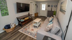 Un salon comprenant un téléviseur, un canapé, une table basse et un tapis décoratif.
