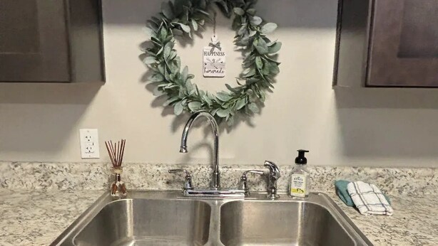A kitchen with a granite countertop, stainless steel sink, and dark wooden cabinets. - Riverside Retreat 2 ~ One Story ~ 3bd/2ba ~ Steps to the River & Main St (Madison)